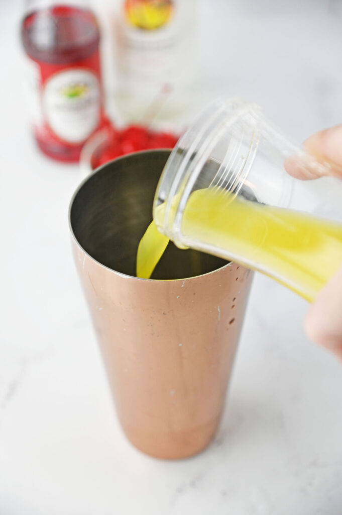 orange juice pouring into a cocktail shaker