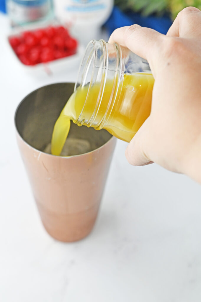 pineapple juice pouring into a cocktail shaker